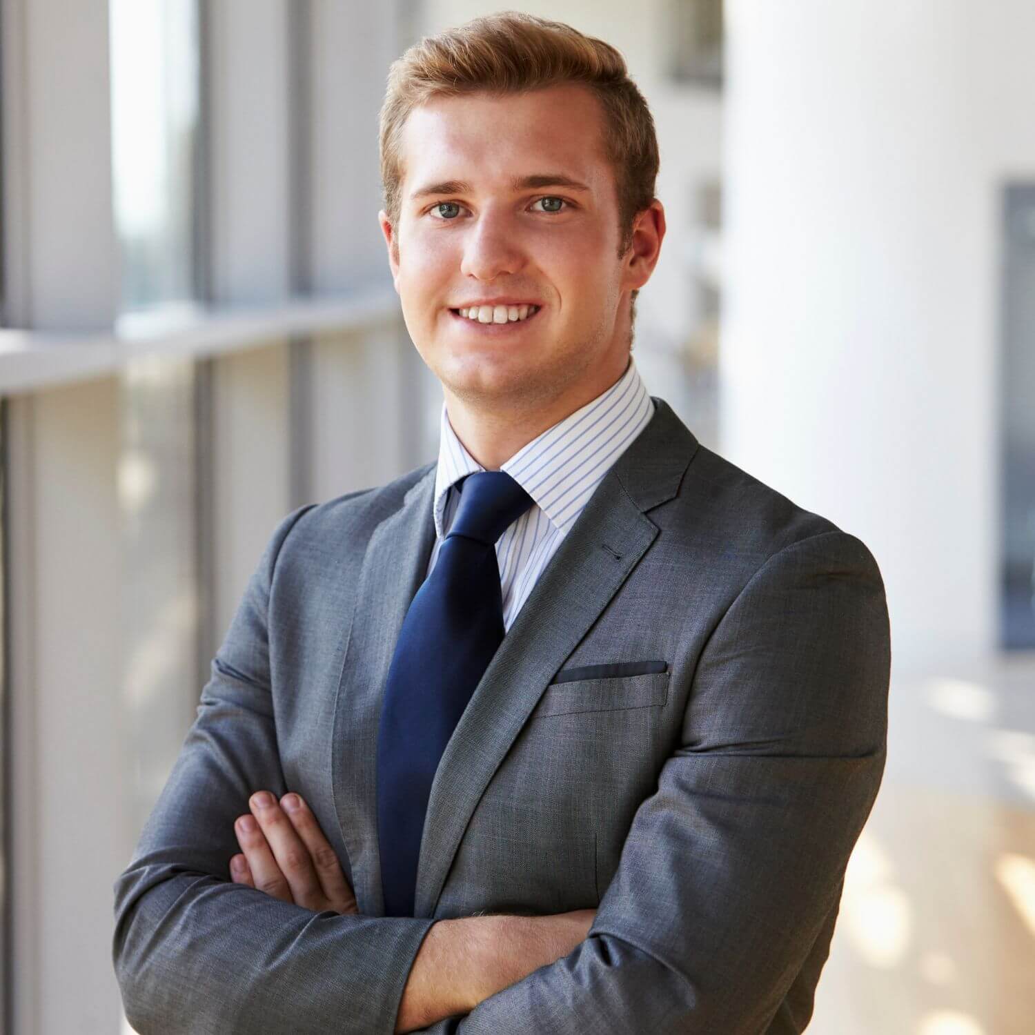 Professionally dressed man smiling in a modern office setting.
